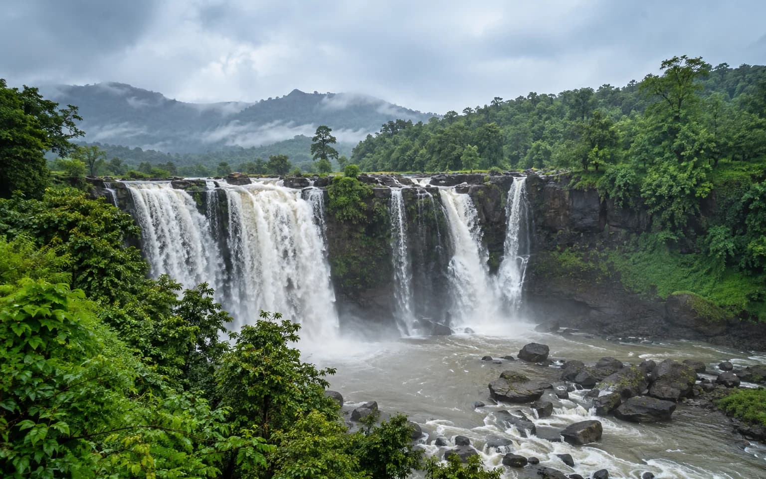 Broad monsoon waterfall surrounded by the green hills near Saputara